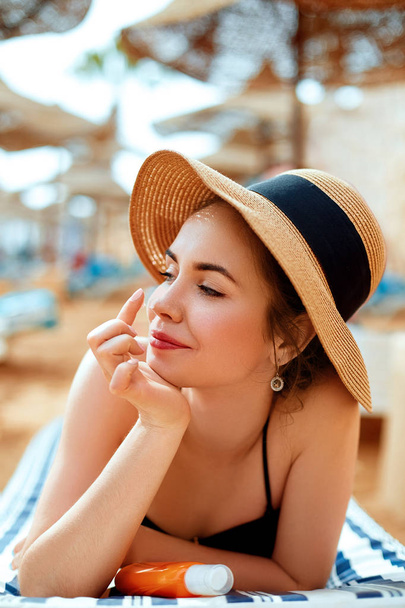 Suntan   woman in hat applying sunscreen solar. Beautiful happy woman smear  lotion  with sun cream   to her nose. Skincare.  - Foto, imagen