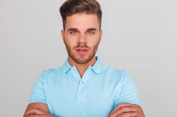 Προσωπογραφία άνδρα με αυτοπεποίθηση φορώντας ένα ελαφρύ μπλε Πόλο μπλουζάκι ενώ στέκεται στο ανοιχτό γκρι φόντο - Φωτογραφία, εικόνα