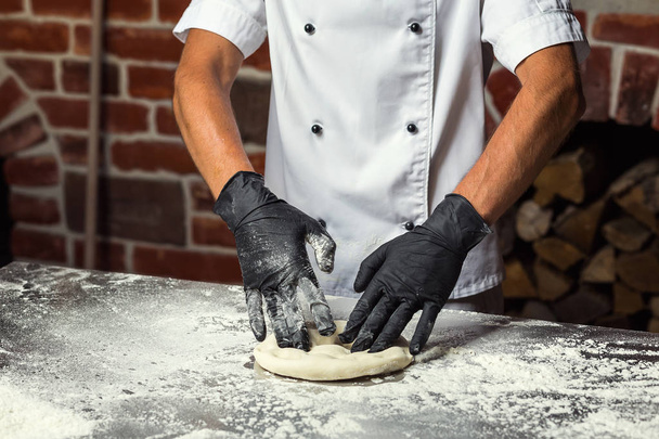 chef che fa la pasta per la pizza. Le mani dell'uomo preparano il pane. Concetto di cottura e pasticceria
 - Foto, immagini