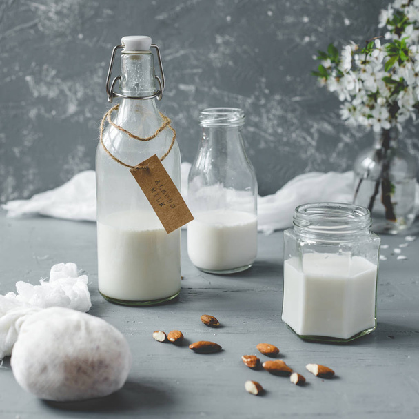 Non-dairy almond milk in glass bottles on wooden background. - Фото, зображення