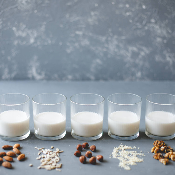 Различные виды веганского немолочного молока в стаканах на деревянном фоне с копировальным пространством
. - Фото, изображение