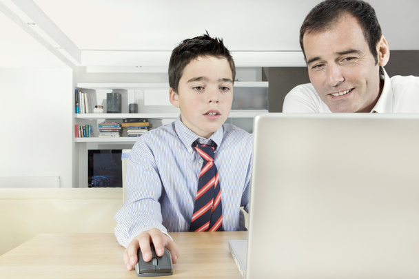 Pai ajudando filho a fazer sua lição de casa em um computador portátil em casa
. - Foto, Imagem