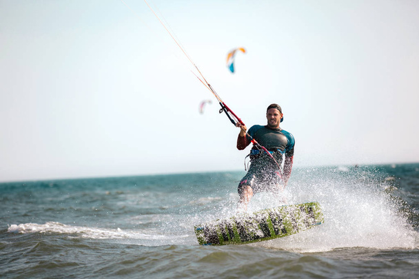 Odvážný muž kitesurfing rychle mezi vlnami  - Fotografie, Obrázek