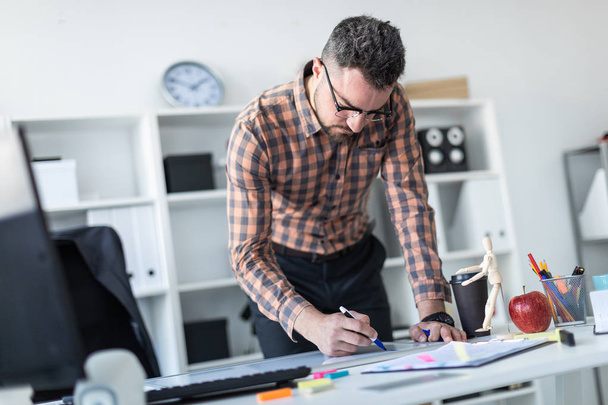 Человек в офисе стоит рядом со столом и рисует маркер на магнитной доске
. - Фото, изображение