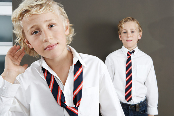 Два брата готовятся к школе дома, в мундирах и галстуках
. - Фото, изображение