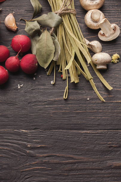 Green italian pasta and cooking ingredients on wooden table - Φωτογραφία, εικόνα