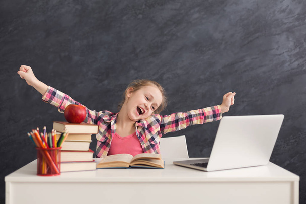 Söpö pieni tyttö venyttely tehdessään läksyjä kannettavalla tietokoneella
 - Valokuva, kuva