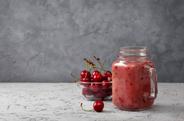 cherry smoothie in Mason jar on a gray concrete background - 写真・画像