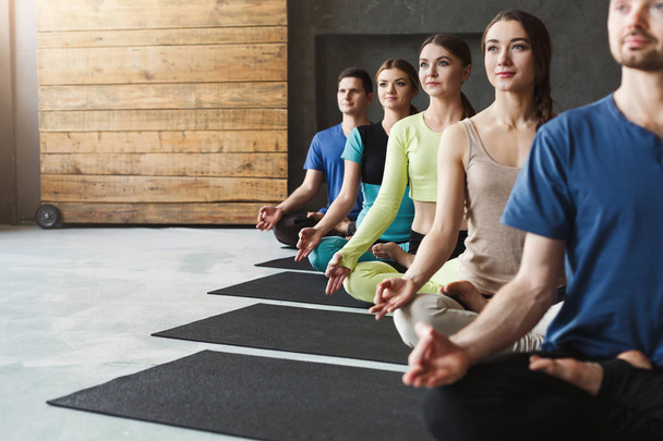 Nuoret naiset ja miehet joogatunnilla, rentoutukaa meditaatio aiheuttaa
 - Valokuva, kuva