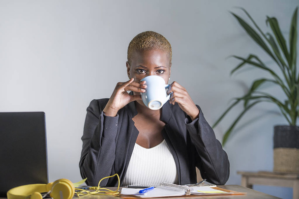 young attractive and trendy black afro american business woman drinking tea or coffee sitting at office computer desk relaxed and satisfied in work lifestyle concept - Фото, изображение