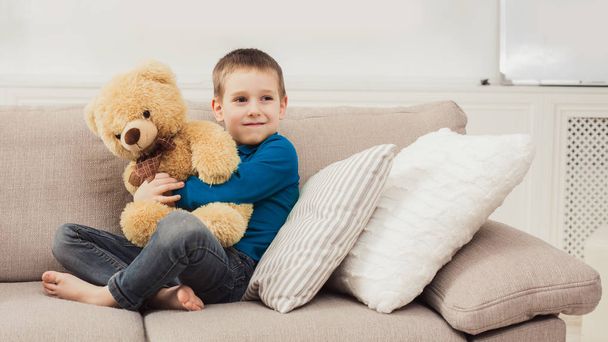 kleines süßes Kind mit Teddybär im Wohnzimmer - Foto, Bild