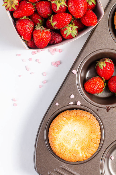 Voedsel concept verse zelfgemaakte Baking cupcake en wilde strawberrys in cupacake pan  - Foto, afbeelding