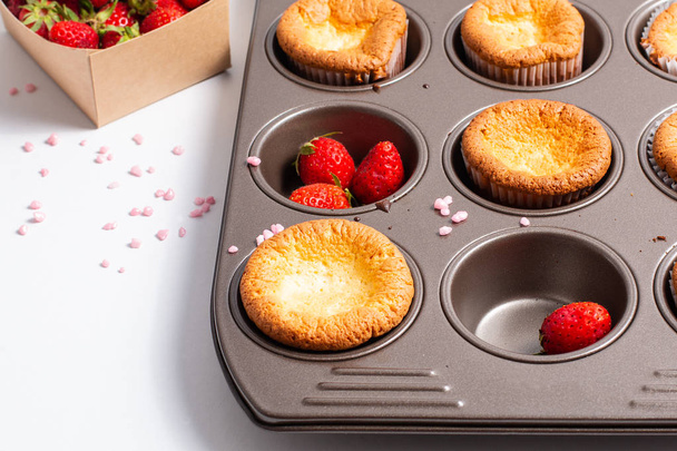 Voedsel concept verse zelfgemaakte Baking cupcake en wilde strawberrys in cupacake pan  - Foto, afbeelding