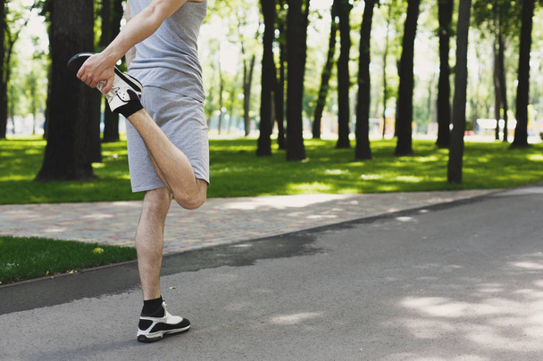 Hombre de fitness irreconocible estirando las piernas al aire libre
 - Foto, Imagen