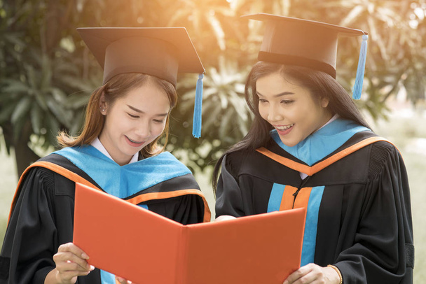Twee vrouwelijke afgestudeerden feliciteren met de graduatie ceremonie. - Foto, afbeelding