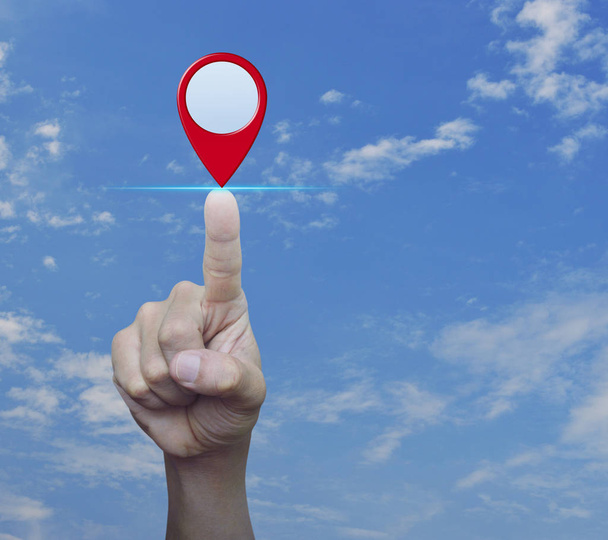 Hand pressing map pin location button over blue sky with white clouds, Map pointer navigation concept - Photo, Image