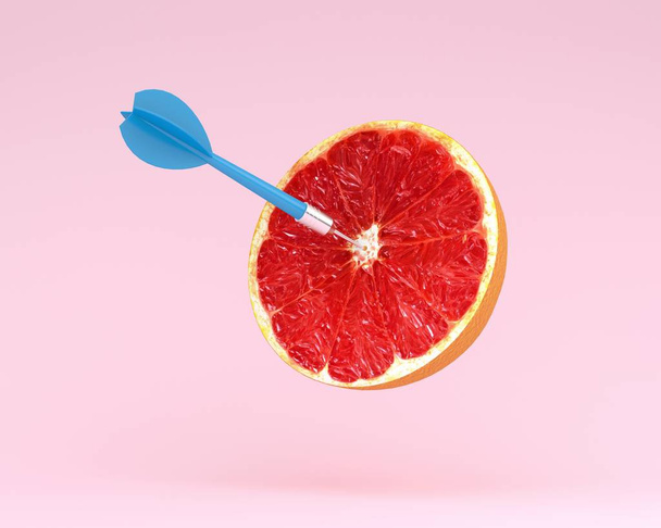 Φέτα γκρέιπφρουτ, φρούτα με κυκλικό στόχος dart σήμανση και μπλε παστέλ ροζ background.minimal ιδέα φαγητό και φρούτα έννοια. Δημιουργική ιδέα να παράγουν έργο και διαφημιστικές επικοινωνίες μάρκετινγκ - Φωτογραφία, εικόνα