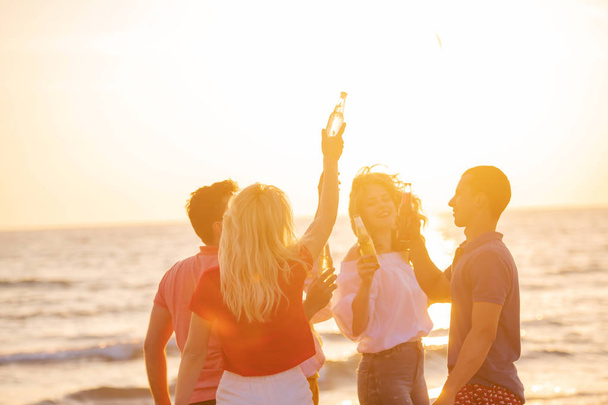 group of happy young people with drinks at the beach on beautiful summer sunset - Photo, Image