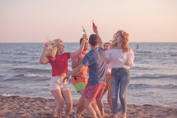 ομάδα ευτυχισμένος νέων ανθρώπων με ποτά στην παραλία στο όμορφο καλοκαιρινό ηλιοβασίλεμα - Φωτογραφία, εικόνα