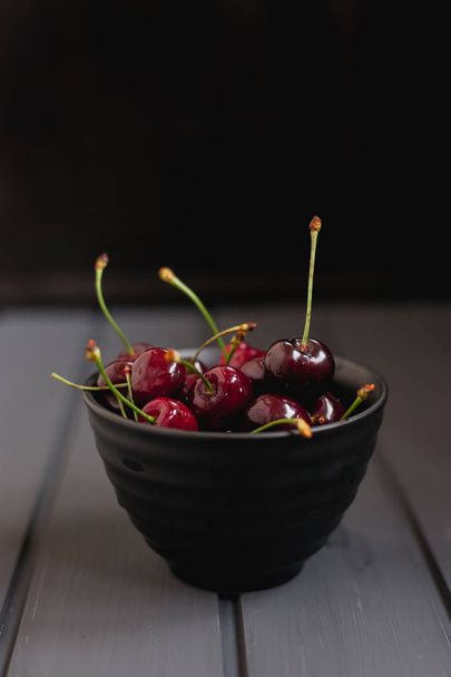 ripe cherry in a bowl on a black background - Photo, Image