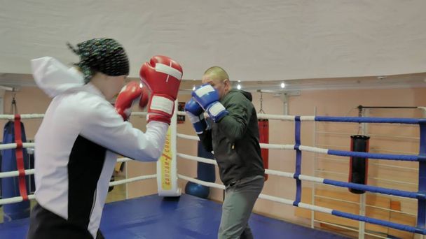 El entrenador lleva a cabo una batalla de entrenamiento con una kickboxer femenina en el ring
 - Foto, Imagen