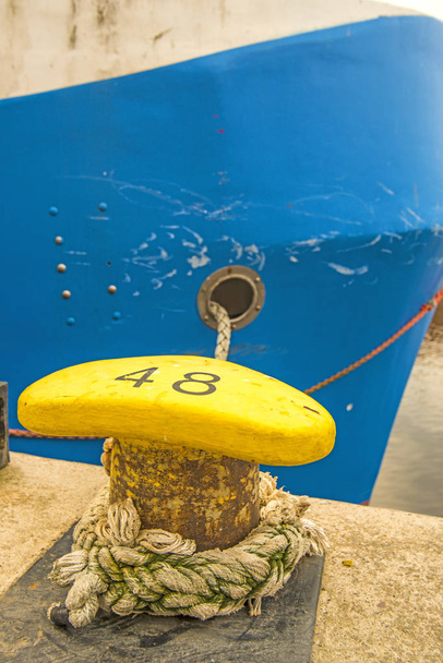боллард з швартовою лінією і синім корпусом корабля
 - Фото, зображення