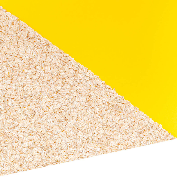 Concept créatif plat vue du dessus des flocons d'avoine pour des aliments biologiques sains et végétariens pour le petit déjeuner sur un fond de papier de couleur jaune vif avec un espace de copie dans un style minimal, modèle carré
 - Photo, image