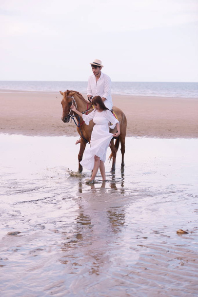 Ρομαντικό ζευγάρι με ιππασία στην παραλία το απόγευμα, στο γλυκό διακοπές - Φωτογραφία, εικόνα