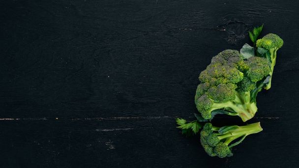 Fresh broccoli. On a black wooden background. Top view. Copy space. - Фото, изображение