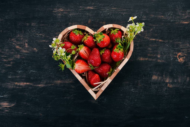 Strawberries in a box in the shape of a heart. On a wooden background. Top view. Copy space. - Fotoğraf, Görsel