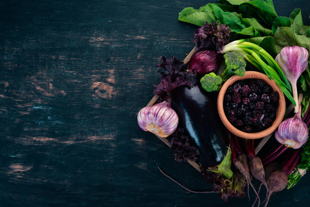Purple food. Fresh vegetables and berries in a wooden box. On a wooden background. Top view. Copy space. - Foto, afbeelding