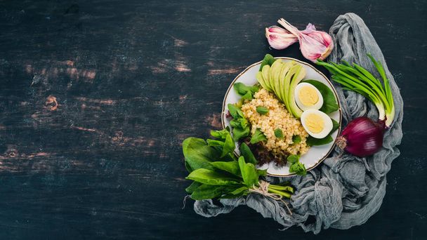Bulgur with avocado, spinach and boiled egg. On a wooden background. Top view. Copy space. - Foto, Bild