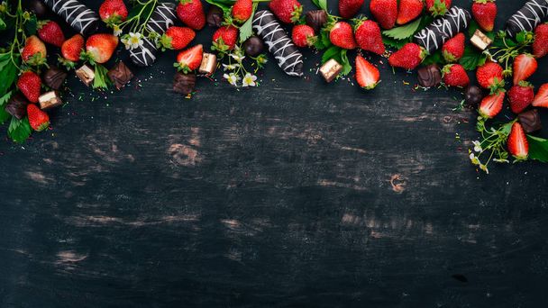 Strawberry with chocolate and candy. On a black wooden background. Top view. Copy space. - Fotó, kép
