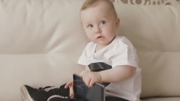 A small child is playing with a smartphone. Family at home - Séquence, vidéo