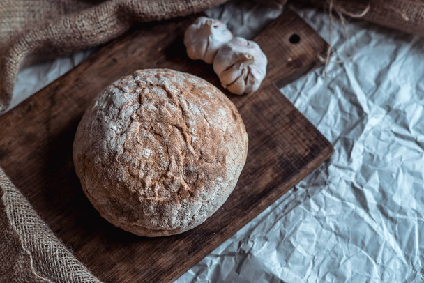 chléb s česnekem a ubrus na hnědé dřevěné desce - Fotografie, Obrázek