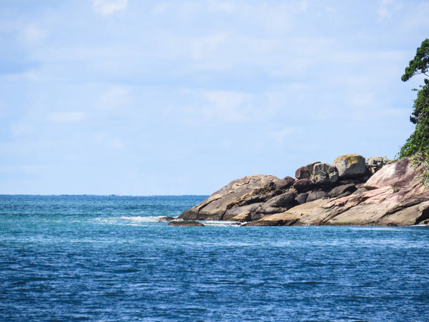 Costa de piedras en el mar, con cielo azul, en día soleado
. - Foto, Imagen