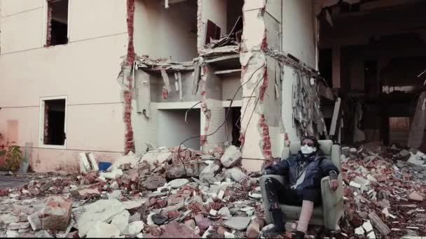 Postapocalypse, samotna młoda kobieta siedzi pośród zniszczone budynki, ruiny - Materiał filmowy, wideo