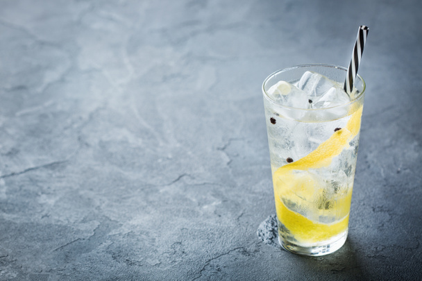 Cibo e bevande, concetto di festa festiva. Gin and tonic drink cocktail alcolico con ghiaccio e scorza di limone in un bicchiere su un tavolo scuro grunge. Copia spazio sfondo
 - Foto, immagini
