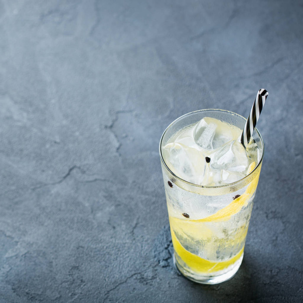 Food and drink, holidays party concept. Gin and tonic alcohol cocktail drink with ice and lemon zest in a glass on a grunge dark table. Copy space background - Valokuva, kuva