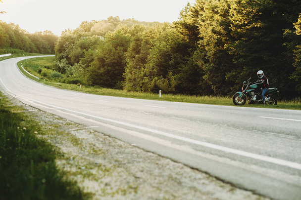 Νέοι Καυκάσιος ταξιδιώτη, ξεκινώντας το ταξίδι του με το ποδήλατό του κοντά στο δρόμο. - Φωτογραφία, εικόνα