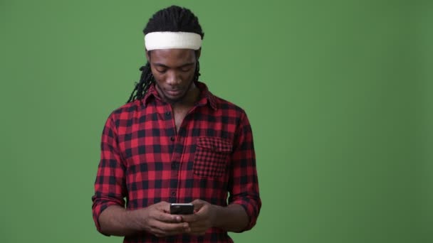 Young handsome African man with dreadlocks against green background - Imágenes, Vídeo