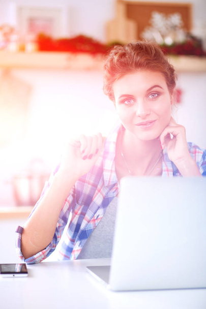 Smiling woman online shopping using computer and credit card in kitchen . Smiling woman - 写真・画像