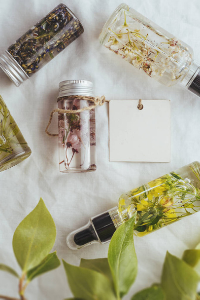 Óleo essencial, etiquetas vazias e flores frescas de amêndoa, sobre fundo folhas verdes
 - Foto, Imagem