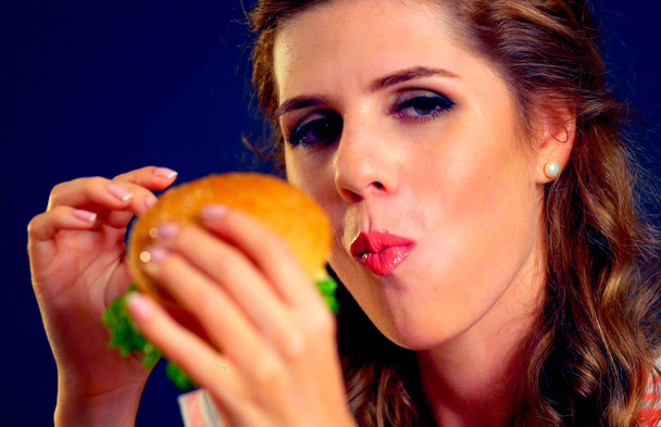 Дівчина відкрив рот, проведення гамбургер розпростертими руками і закрив очі. - Фото, зображення