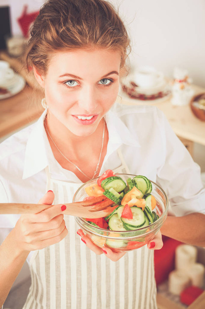 Smiling young woman preparing salad in the kitchen. - Valokuva, kuva