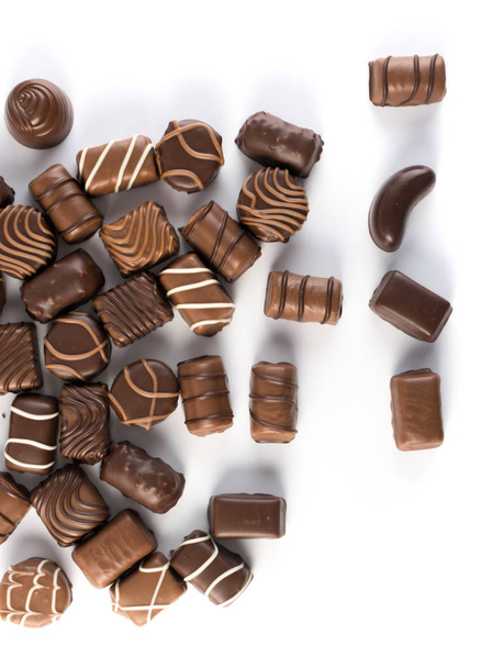 Hermosos dulces de chocolate creativos aislados sobre fondo blanco. Chocolates dispersos vista superior y plano laico
 - Foto, Imagen