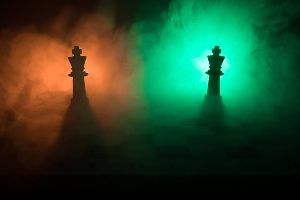 Chess board game concept of business ideas and competition and strategy ideas concep. Chess figures on a dark background with smoke and fog. Business leadership and confidence concept. Selective focus - Photo, Image