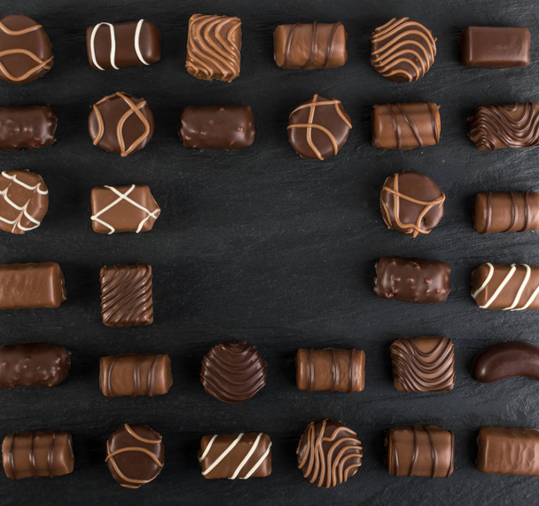 Krásná kreativní čokoládové sladkosti na přirozená černého kamene. Mix čokolád pohled shora a ploché ležela s místem pro Text - Fotografie, Obrázek