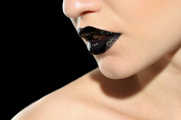 Beautiful young model with creative lips makeup on black background - Fotó, kép