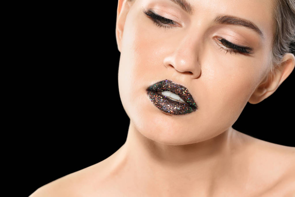 Beautiful young model with creative lips makeup on black background - Foto, Imagen